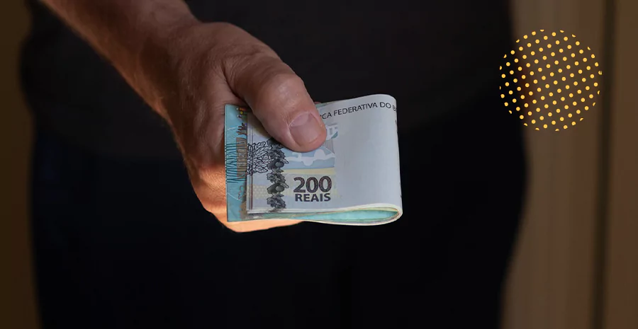 Homem segurando um bole de notas de duzentos reais